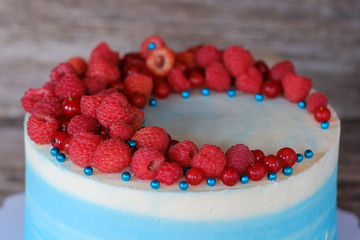 beautiful homemade cake with blue cream and raspberry and currant berries