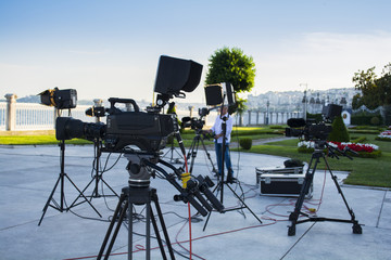broadcast tv; movie shooting or video production and film, tv crew team with camera, light and audio equipment at outdoor location