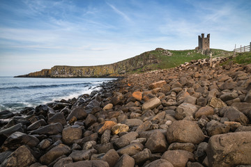 Landscape image of Dunstanburgh Castle on Northumberland coastline in England during late Spring...