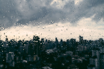 Rain over Bangkok: Out of focus cityscape behind the window glass with rain drops. - obrazy, fototapety, plakaty