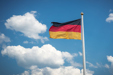 flag of Germany in the sky/ flag of Germany in the wind on a flagpole against a background of clouds in the sky