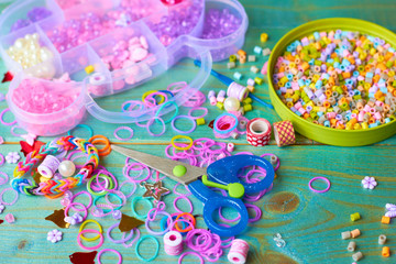  On the table scattered beads, colored rubber bands and ribbons.