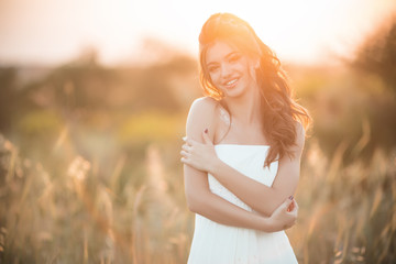 Fototapeta na wymiar Portrait of beautiful happy young bride in field over sunset lights