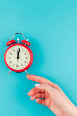 Woman hand holding the red vintage alarm clock