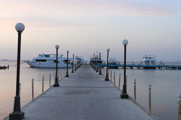 Pier and ships on the sea. The pre-dawn sky. A minute before sunrise. Red sea,  Egypt.