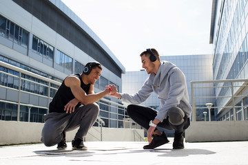 Two friends in the morning training. Rest after a hard workout. Sport in an urban environment. Athletes smile after a hard workout. The photo represents a healthy lifestyle and love for sports.