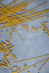 Variety types of pasta on a gray concrete background.