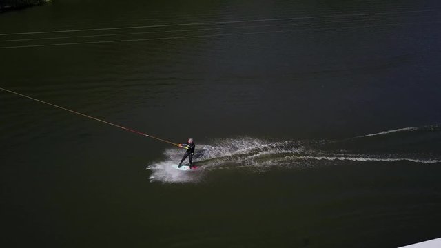Aerial shot of a cableway in a lake with a wakeboarder grinding and rotating on a funbox