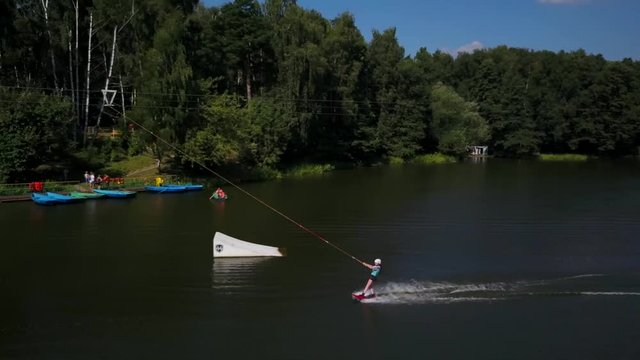 Aerial shot of a cableway in a lake with a wakeboarder grinding and rotating on a funbox