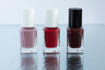 Set of bottles of nail polish on glass table background. Manicure concept. Beauty colors for choice.