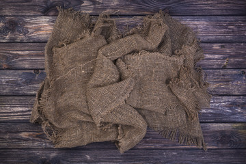 Burlap on black wooden background, top view