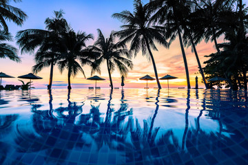 Summer beach holiday vacation destination, luxurious beachfront resort swimming pool with tropical landscape, quiet warm sunset, silhouette and reflection in water - obrazy, fototapety, plakaty