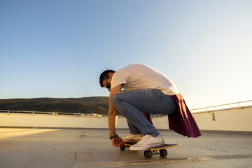 PORTRAIT OF A CAREFREE MAN DRIVING SKATEBOARD ON THE TERRACE. Young and careless having fun concept.