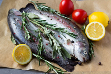 Two fresh raw salmon with lemons, tomatoes and greens.