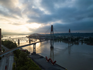 Aerial Panoramic view of Fraser River and Bridges during a vibrant sunrise. Taken in New Westminster, Greater Vancouver, British Columbia, Canada.