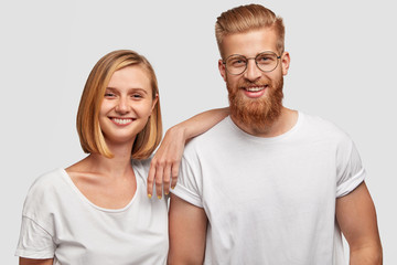 Portrait of cheerful young female and male friends have fun together, dressed in casual outfit, isolated over white background. Positive female with bobbed hairstyle and her bearded companion