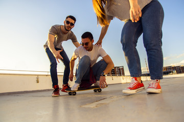 Skateboard friends riding skateboard on the balcony on sunny day. Young and careless friends having...
