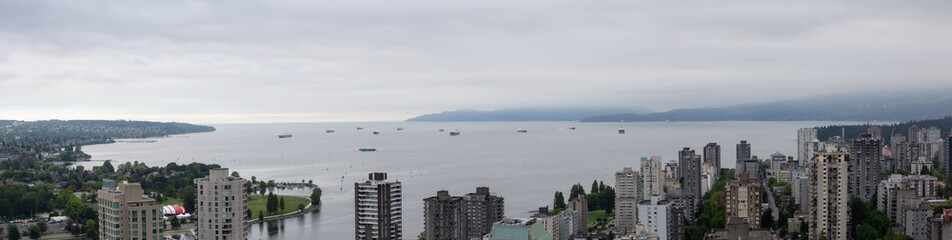 Aerial panoramic view of Downtown City Buildings overlooking the ocean during a cloudy overcast day. Taken in Vancouver, BC, Canada.