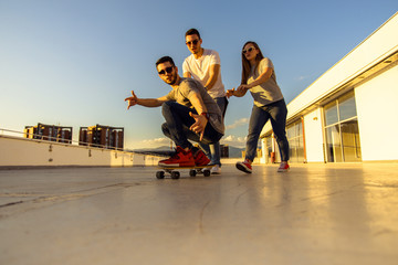 YOUNG FRIENDS WITH SKATEBOARD AT THE TOP OF THE BUILDING AT SUNSET. Young and careless friends...