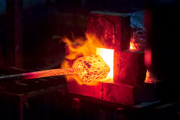 Burning  in a blacksmith forge.  Making metal items in smithy. In the smithy a red-hot iron piece...