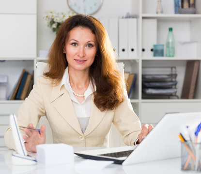 Portrait of businesswoman who is working with documents behind laptop