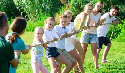 Glad kids with moms and dads playing tug of war