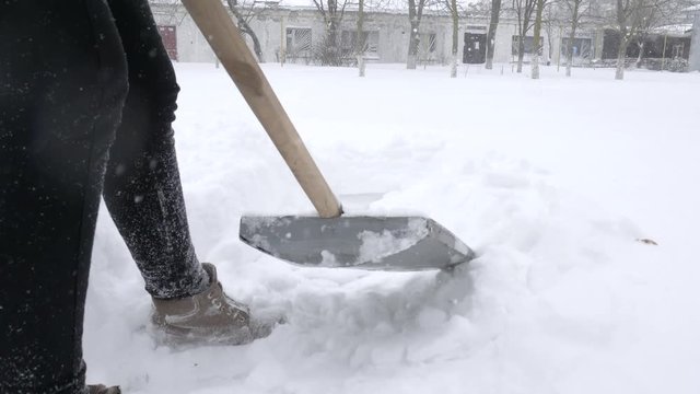 cold winter morning, people manually shoveling snow from street during snowstorm close-up