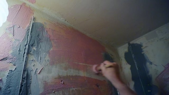 man's hand with a brush paints old wall.