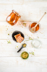 Organic floral honey, in jars, with pollen and honey combs, on a white wooden table, with wildflowers, copy space top view