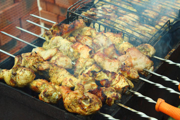 Preparation of a shish kebab from a chicken on a brazier on skewers. Close-up. Chicken shish kebab. Background.