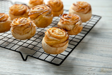 Cooling rack with apple roses from puff pastry on wooden background