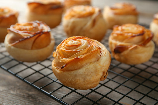 Cooling rack with apple roses from puff pastry on table, closeup