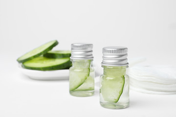 Obraz na płótnie Canvas Bottles with cucumber water on light background. Fresh skin care tonic