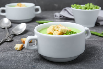 Green pea soup with croutons in bowl on table