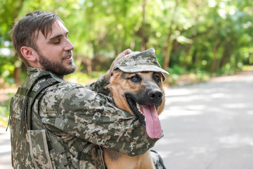 Man in military uniform with German shepherd dog outdoors