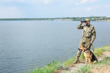 Naklejka premium Man in military uniform with German shepherd dog outdoors