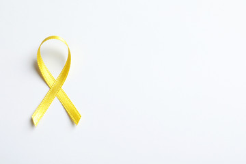 Yellow ribbon on white background, top view. Cancer awareness