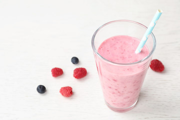 Delicious smoothie with raspberries in glass on table