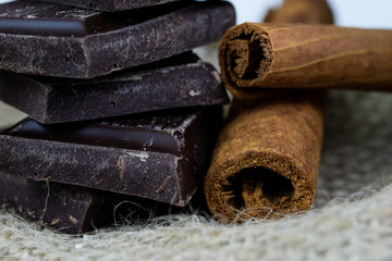 Chocolate in cubes and cinnamon arranged on the kitchen table. Sweet dessert on a linen napkin.