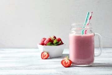 Mason jar with tasty strawberry smoothie on table