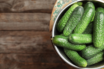 Bowl with ripe fresh cucumbers on table, top view