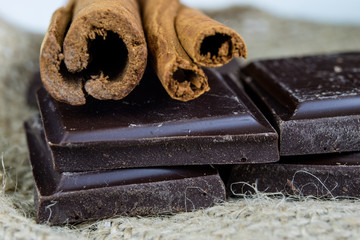 Chocolate in cubes and cinnamon arranged on the kitchen table. Sweet dessert on a linen napkin.