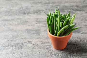 Pot with fresh green French beans on table