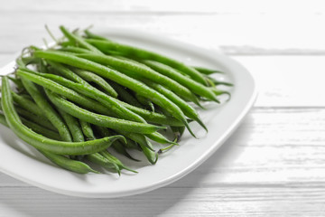Plate with fresh green French beans on table, closeup