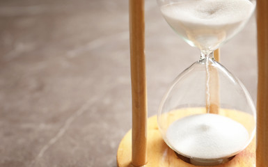 Hourglass with flowing sand on table. Time management