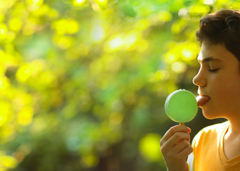 handsome teenager boy with pistachio mint eskimo ice cream on stick on summer sunny garden...