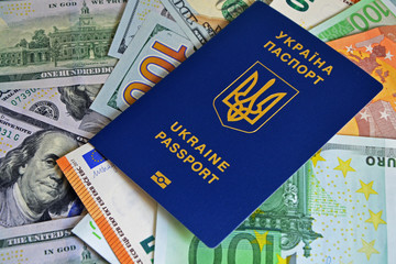 The Ukrainian biometric passport is on paper euro bills and dollars. Concept: increase of salaries, Ukrainians go abroad to work in Europe, Immigration to work, vacation abroad, visa for Europe.