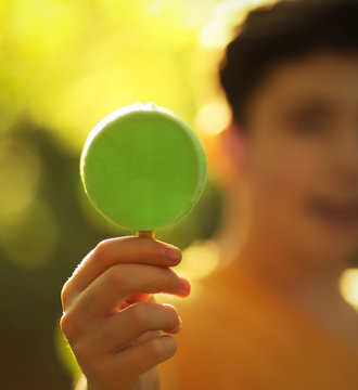 handsome teenager boy with pistachio mint eskimo ice cream on stick on summer sunny garden background close up photo
