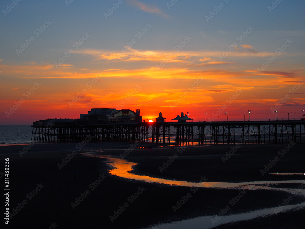 Wall mural scenic view of blackpool north pier in glowing red evening light at sunset with illuminated pink and