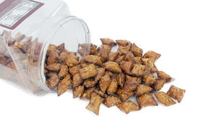 Peanut butter pretzels spilling from clear plastic container. Isolated.